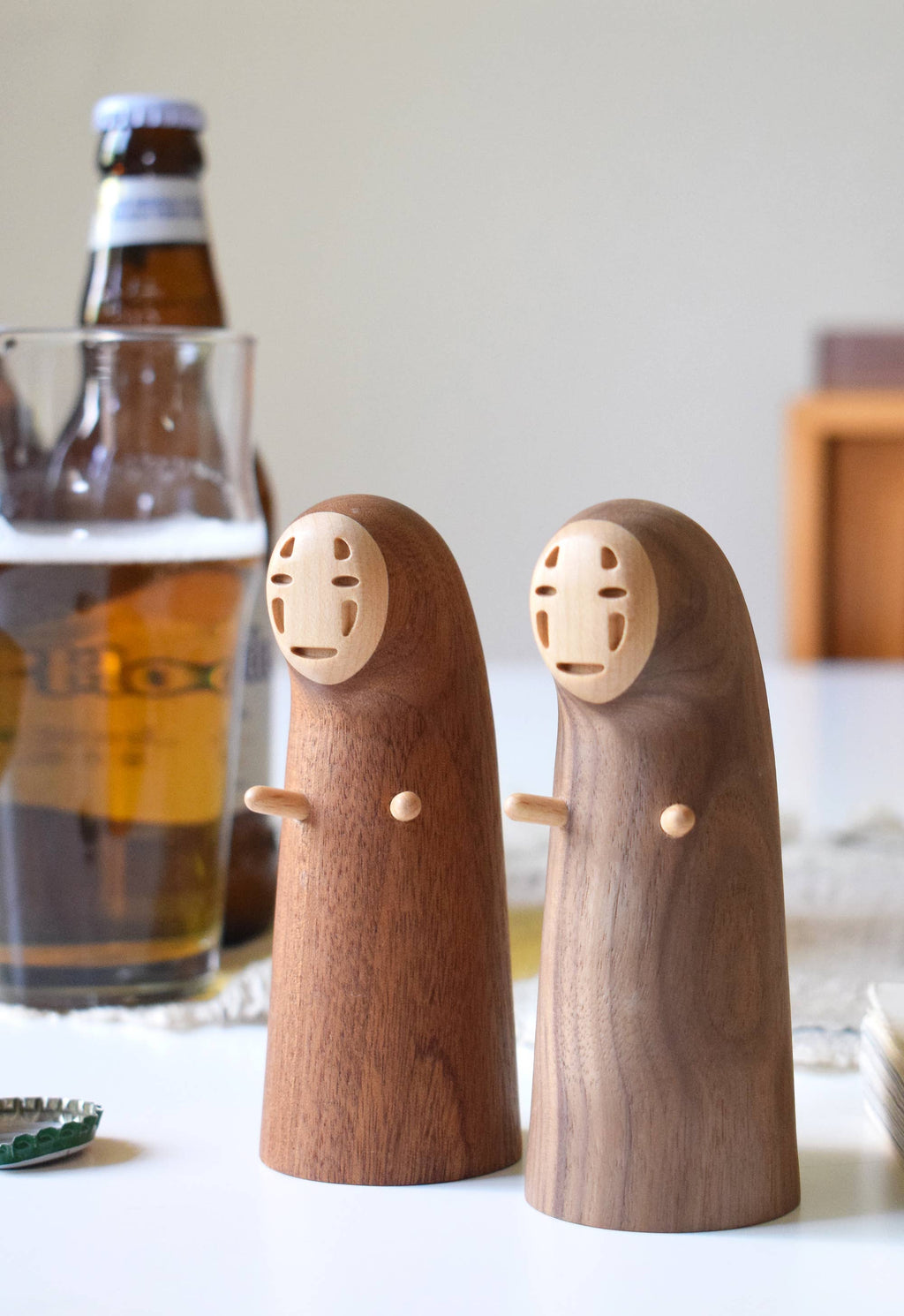 Wooden figures resembling characters from a movie on a table with a beer bottle in the background.
